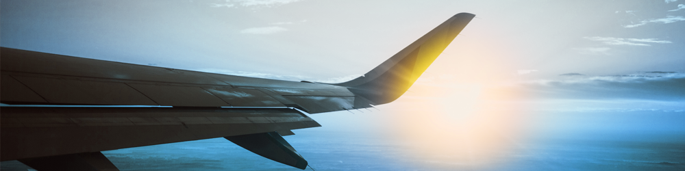 Wing of an airplane with sun in background